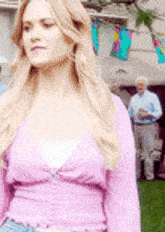 a woman in a pink sweater is standing in front of a man in a blue shirt