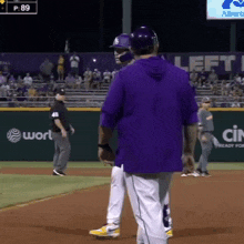 a man in a purple shirt stands on a baseball field with a sign that says left