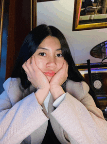 a woman rests her head on her hands while wearing a jacket