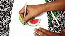 a person is drawing a slice of watermelon on a piece of paper