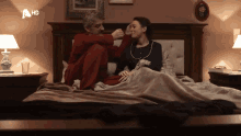 a man and a woman are sitting on a bed with a hd logo on the bottom right
