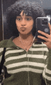 a woman is taking a selfie in front of a mirror .