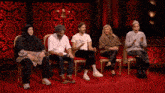 a group of people sitting on a red carpet