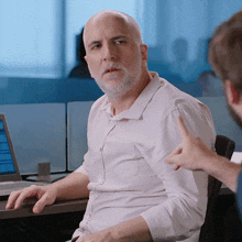 a man with a beard sits at a desk with a laptop