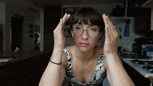 a woman wearing glasses is making a funny face in front of a microwave