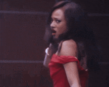 the woman is wearing a red off the shoulder dress