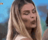 a woman with long blonde hair is blowing a kiss .