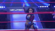 a woman is in a wrestling ring with her hand in the air