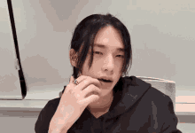 a young man with long black hair has a ring on his finger