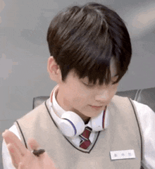 a young boy wearing headphones and a vest and tie is holding a small bug .