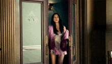 a woman in a pink fur coat is standing in front of a door