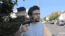 a man is holding a gun in front of a sign that says gifrun.com