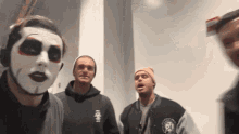 a man with a mask on his face stands in a room with other men