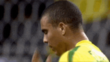 a close up of a man 's head with a yellow shirt with the number 5 on it .