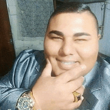 a man wearing a watch and a ring is smiling for the camera