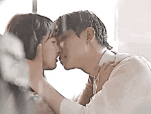 a man and a woman are kissing in front of a window .