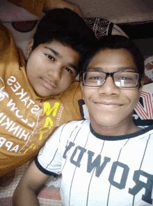 two boys are posing for a picture and one is wearing a shirt that says " kowos "