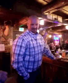a man in a plaid shirt is standing in a dark room