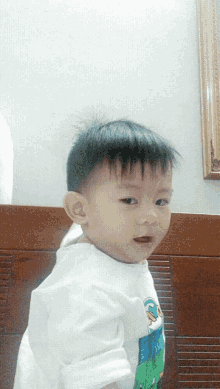 a baby wearing a white shirt with a picture of a duck on it