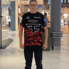 a young man wearing a nissan fuel shirt stands in a mall