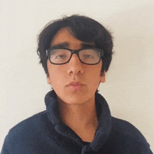 a young man wearing glasses and a blue jacket