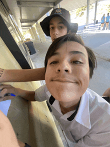 a boy wearing a hat with a cross on it is standing next to another boy