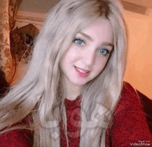 a girl with long blonde hair and blue eyes is smiling for the camera