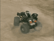 a batman monster truck is driving on a dirt track