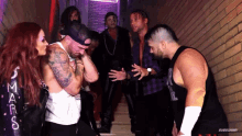 a group of wrestlers are standing in a hallway and one of them has a shirt that says smackdown on it
