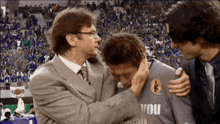 a man in a suit is hugging a man in a shirt that says voli