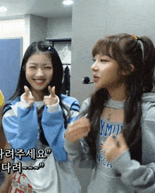 a girl wearing a sweatshirt with the word ymud on it stands next to another girl
