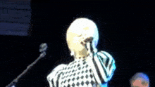 a woman is singing into a microphone in a dark room