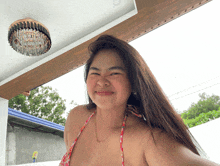 a woman in a bikini is making a funny face in front of a chandelier
