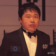 a man in a tuxedo and bow tie has the number 039 on his chest