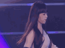 a woman with long black hair is standing on a stage in front of a spotlight .