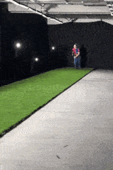 a man in a red and blue shirt is running on a concrete track