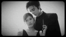 a black and white photo of a man and woman standing next to each other