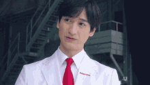 a man wearing a white lab coat and red tie has a sticker on his jacket that says adarami on it