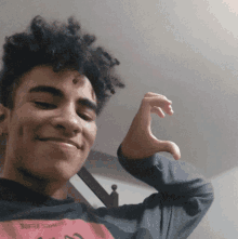 a young man making a heart shape with his hands while wearing a shirt that says " come back "