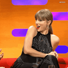 a woman in a black dress is sitting on a red couch with swiftgifs written on the bottom