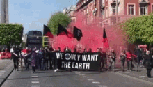 a group of people march down a street holding a banner that says we only want the earth
