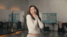 a woman in a white crop top and grey sweatpants