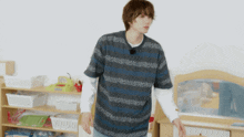 a man in a blue and white striped shirt stands in front of a shelf