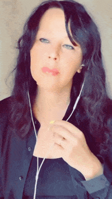 a woman wearing a black shirt and earbuds looks at the camera
