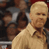 a man in a striped shirt stands in front of a wrestling ring