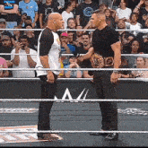 two men are standing in a wrestling ring with a crowd behind them