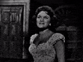 a woman in a white dress is singing in front of a door