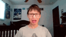 a young boy wearing glasses is making a funny face in a bedroom .