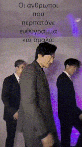 three men in suits are standing next to each other with purple lights behind them and a sign that says " οι ανδρωποι που "