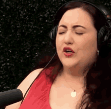 a woman wearing headphones singing into a microphone with her eyes closed